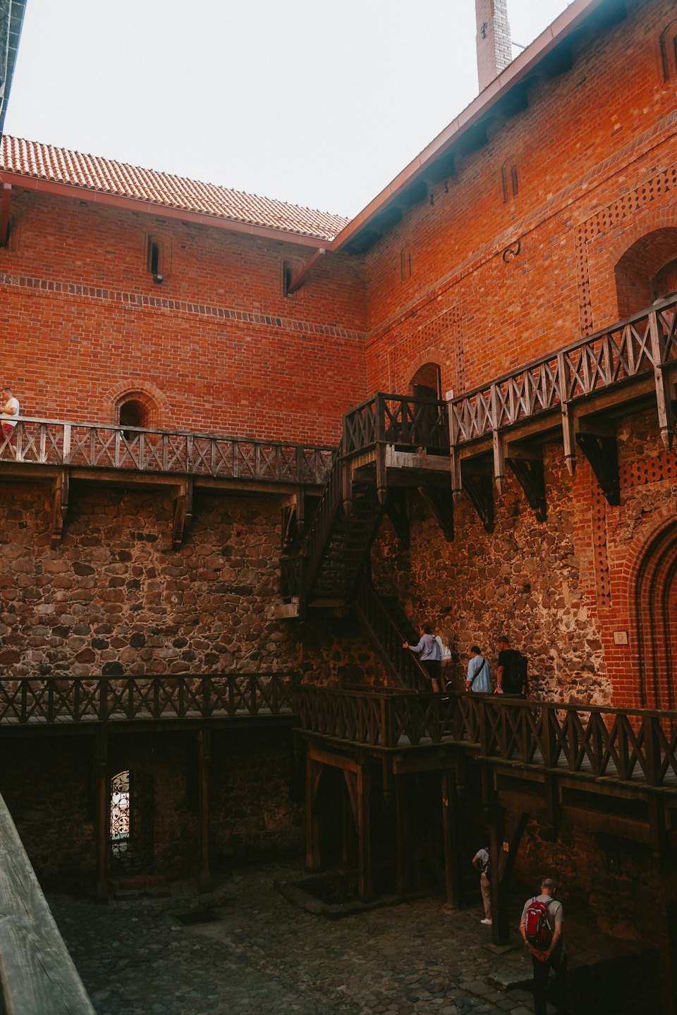 Besucher gehen über Holztreppen in einem historischen Steinschloss.